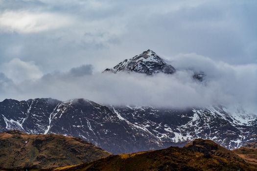 Peak of Mount Snowdon in Wales UK partially covered by cloud and snow