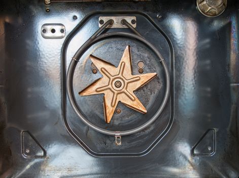 Old discoloured fan exposed in oven after cover removed and showing heating element