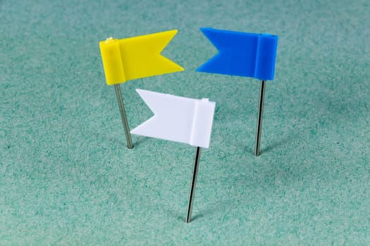 Yellow, Blue and White flag pins on a green background