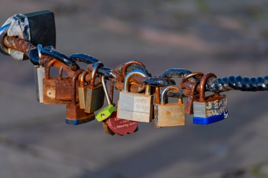 Old rusty Love Lock padlocks attached to a chain fence