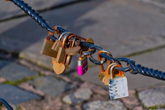 Old rusty Love Lock padlocks attached to a chain fence