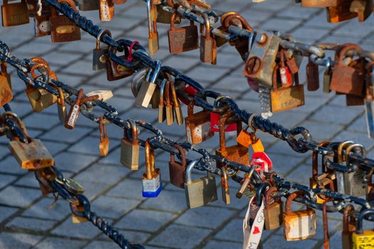 Old rusty Love Lock padlocks attached to a chain fence