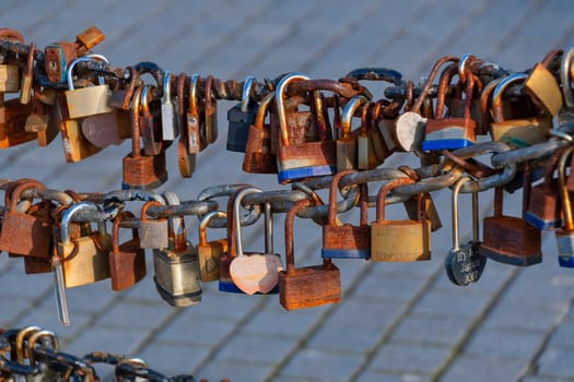 Old rusty Love Lock padlocks attached to a chain fence