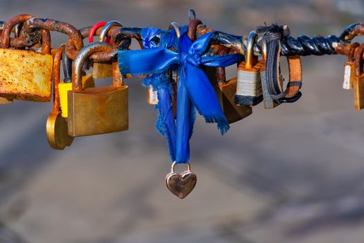 Old rusty Love Lock padlocks attached to a chain fence