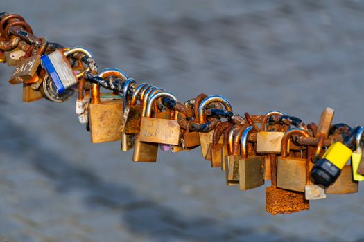 Old rusty Love Lock padlocks attached to a chain fence