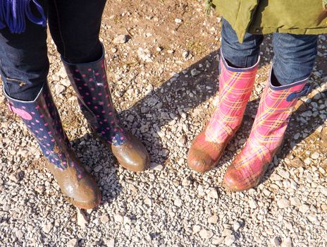 Two people wearing muddy Wellington boots.