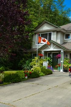 Main entrance of family house with canadian flag in front. Fragment of residential house with concrete driveway