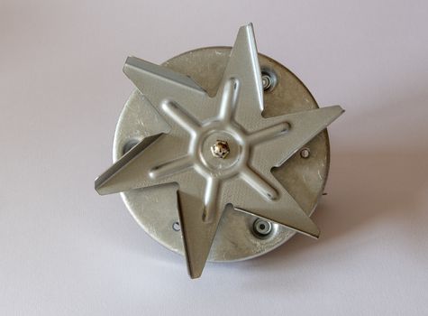 New fan ready to be fitted to an oven on a plain background