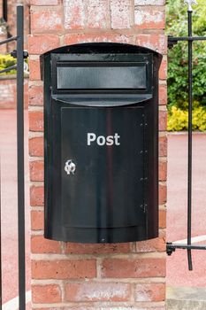 Black post box on a brick wall