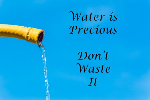 A yellow hose with a trickle of water and the words Water is Precious Don't Waste It