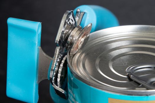 Close view of a can opener opening a tin can