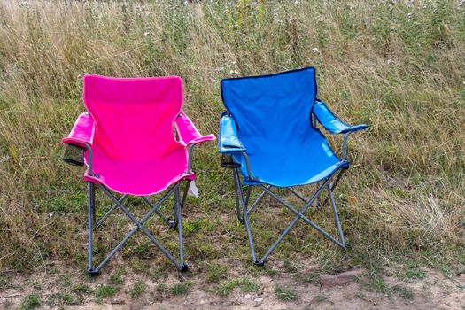 Pink and blue folding camping chairs in a field