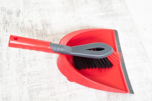 Red and grey dustpan and brush on a light background