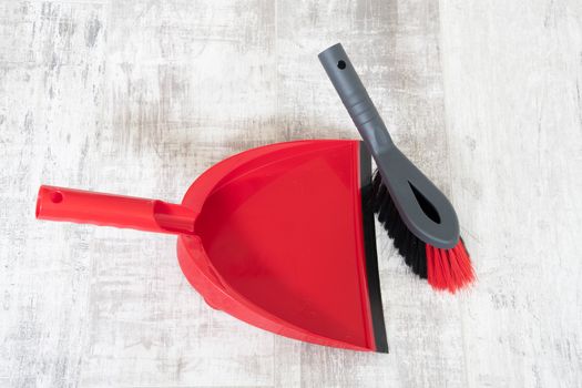 Red and grey dustpan and brush on a light background