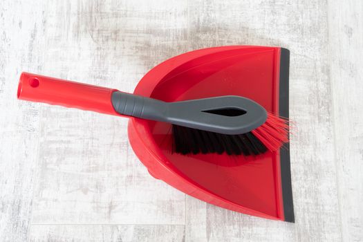 Red and grey dustpan and brush on a light background