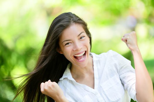 Portrait of successful young woman with clenched fists. Attractive female is celebrating victory. She is in casuals at park.