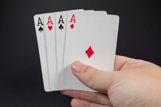 A hand holding the four Aces from playing cards