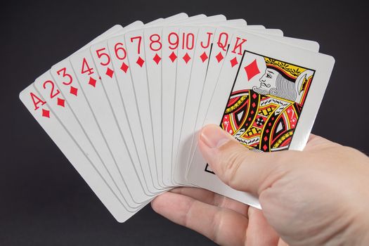 A hand holding the suit of Diamonds from playing cards