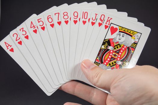 A hand holding the suit of Hearts from playing cards
