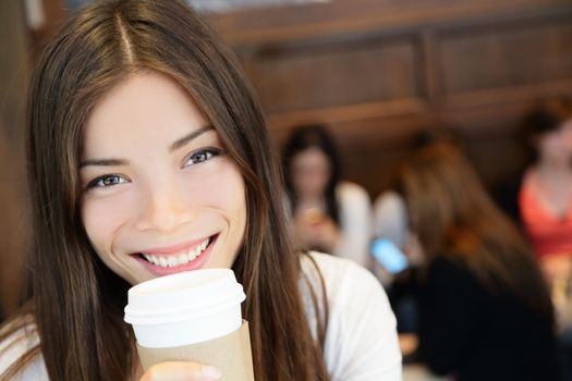 Portrait of young woman having coffee. Smiling beautiful mixed race Asian / Caucasian female is with disposable cup. She is in coffee shop.