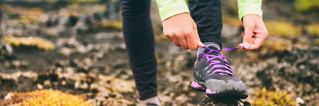 Trail run athlete woman tying laces of running shoes, getting ready for training cardio exercise. Panoramic banner of sneakers.