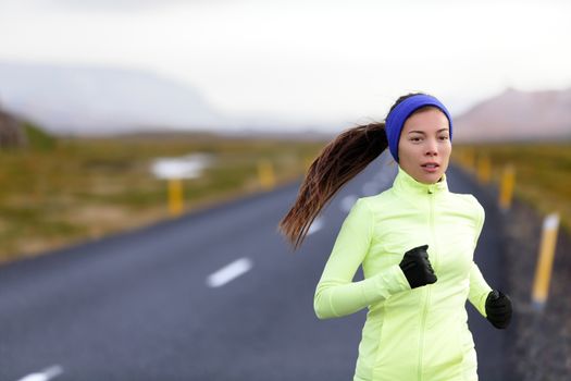 Female runner running in warm clothing for winter and autumn outside. Woman runner training in cold weather living healthy active lifestyle.