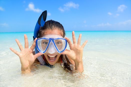 Beach vacation fun woman wearing a snorkel scuba mask making a goofy face while swimming in ocean water. Closeup portrait of Asian girl on her travel holidays. Summer or winter destination.