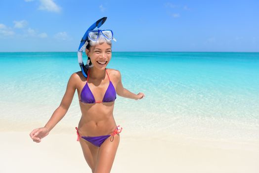 Beach vacations - Asian woman swimming having fun. Beautiful sexy young female adult running out of the water in snorkel scuba mask and purple bikini laughing during her travel holidays.
