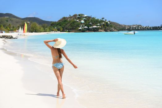 Beach travel vacation woman in bikini wearing beach hat, joyful and free on holidays on Jolly Beach, Antigua Girl on travel vacation holidays having fun. Asian Chinese Caucasian female model.