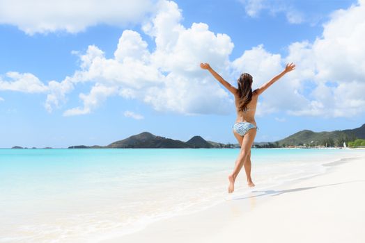 Beach, travel and vacation holidays concept with bikini girl happy running full of joy and aspiration on pristine beautiful Caribbean beach with turquoise water. Woman on Jolly Beach, Antigua.