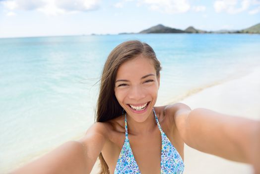 Summer vacation beach travel. Technology and people concept with smiling woman making selfie with smartphone on beach. Happy mixed race Caucasian / Asian Chinese woman taking self portrait having fun.