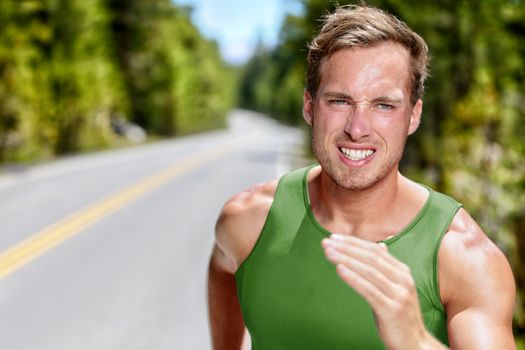 Athlete on intense cardio running workout. Closeup portrait of male sprinter or long distance runner in hard endurance training on mountain road in summer nature. Determination, focus concept.
