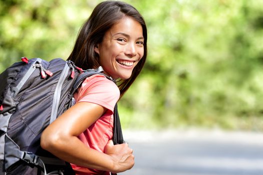 Happy young Asian Chinese backpack girl student. Cute adult woman backpacker smiling at camera with school bag doing summer backpacking travel in nature.