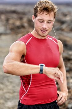 Runner looking at his heart rate monitor, activity tracker smartwatch. Active athlete looking at his smart watch using app after cardio workout for pace and distance information.
