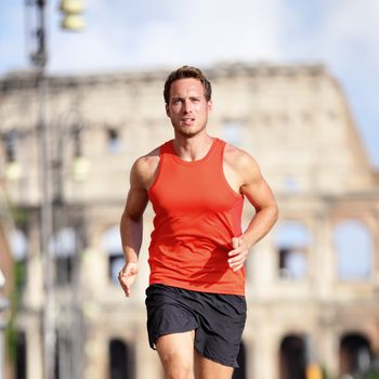 Runner man running at italian city Rome marathon near Colosseum, Roma, Italy. Handsome male athlete training cardio jogging on street with famous touristic attraction landmark in the background.