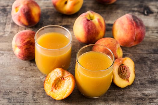 Natural peach juice in glass on wooden background