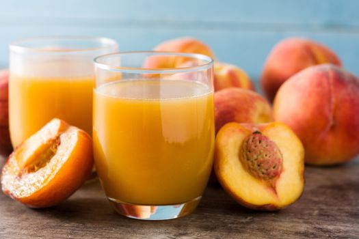 Natural peach juice in glass on wooden table