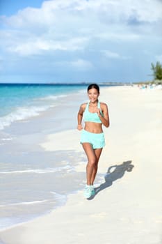 Happy jogging woman running on sunny beach living a fit and active life. Happiness and health concept on summer vacation travel beach.