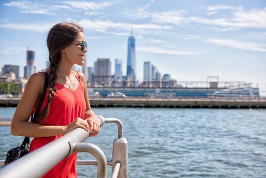 New York City travel - Tourist woman on summer travel looking at waterfront view of skyline with one tower building in the background.