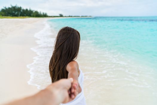 Couple summer vacation travel - Woman walking on romantic honeymoon beach holidays holding hand of boyfriend following her, view from behind. POV.