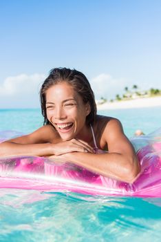 Happy beach woman swimming in ocean pristine turquoise water float air bed mattress floating toy. Asian young girl having fun with pool accessory at Caribbean holiday resort.