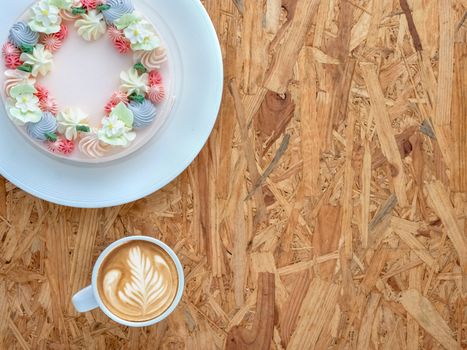 Beautifully decorated cake with cup of coffee on rustic wooden board background. top view, flat lay, copy space.