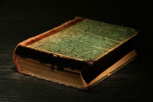 Very old book on black table under beam of light