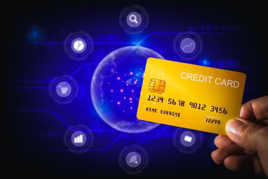 Shopping online concept. Hand holding yellow credit card on blue technology background. Digital payment for shopping at home.