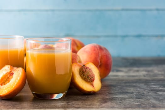 Natural peach juice in glass on wooden background
