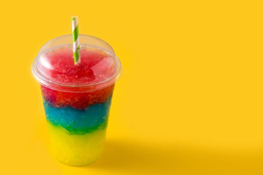 Colorful slushie of differents flavors with straw on yellow background