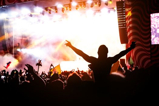 Silhouette of man with raised hands on music concert.