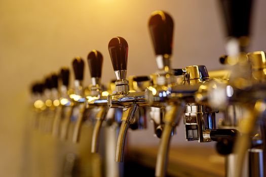 A row of beer taps in a bar.