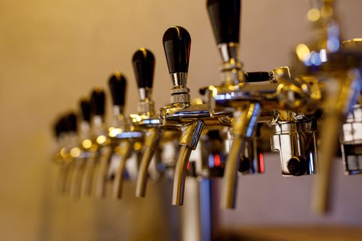 A row of beer taps in a bar.