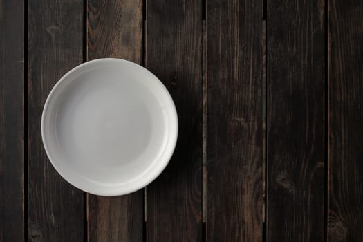 Empty white plate on a wooden loft table. High-quality photo